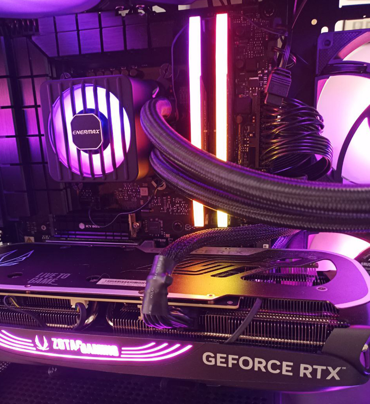 Innenansicht PC mit GeForce RTX 4080 und neuer Enermax LiqMax Flow 360 mm Dual-Chamber-ARGB-Wasserkühlung, Enermax-Logo, lautlose Pumpe, stabile CPU-Temperaturen (Computerheld Linz, Aug 2025) Das Foto zeigt erneut die Innenansicht eines modernen PC-Gehäuses, mit dem dominanten Mainboard und der kraftvollen GeForce RTX 4080 im Vordergrund. Doch das eigentliche Augenmerk liegt – wie schon beim vorigen Bild – auf der Kühlung oberhalb der Grafikkarte. Diesmal ist allerdings nicht mehr die modifizierte Hi-Tech-Variante zu sehen, sondern die frisch eingebaute Original Enermax LiqMax Flow 360 mm. Das neue Modell besticht durch seine Dual-Chamber-Pumpe, auf deren Oberseite zusätzlich ein kleiner Lüfter sitzt. Auch diese AiO ist ARGB-beleuchtet und erstrahlt in einem harmonischen Lila-Weiß-Profil, doch im Gegensatz zum vorigen Foto leuchtet nun wieder das offizielle Enermax-Logo. Der Unterschied ist nicht nur optischer Natur: Die Pumpe arbeitet lautlos, kein Rattern, kein Vibrieren mehr. Damit ist auch das technische Problem gelöst: Der zuvor überhitzte Intel Core i9-14900KF läuft dank der neuen Kühlung endlich wieder im gesunden Temperaturbereich – sowohl im Leerlauf als auch unter Volllast. Dieses Bild aus August 2025 dient im Artikel als dekoratives, zugleich dokumentarisches Beispiel dafür, wie ein fachgerechter Austausch einer defekten All-in-One-Wasserkühlung das System zuverlässig zurück in den grünen Bereich bringt. Einbau Computerheld Linz